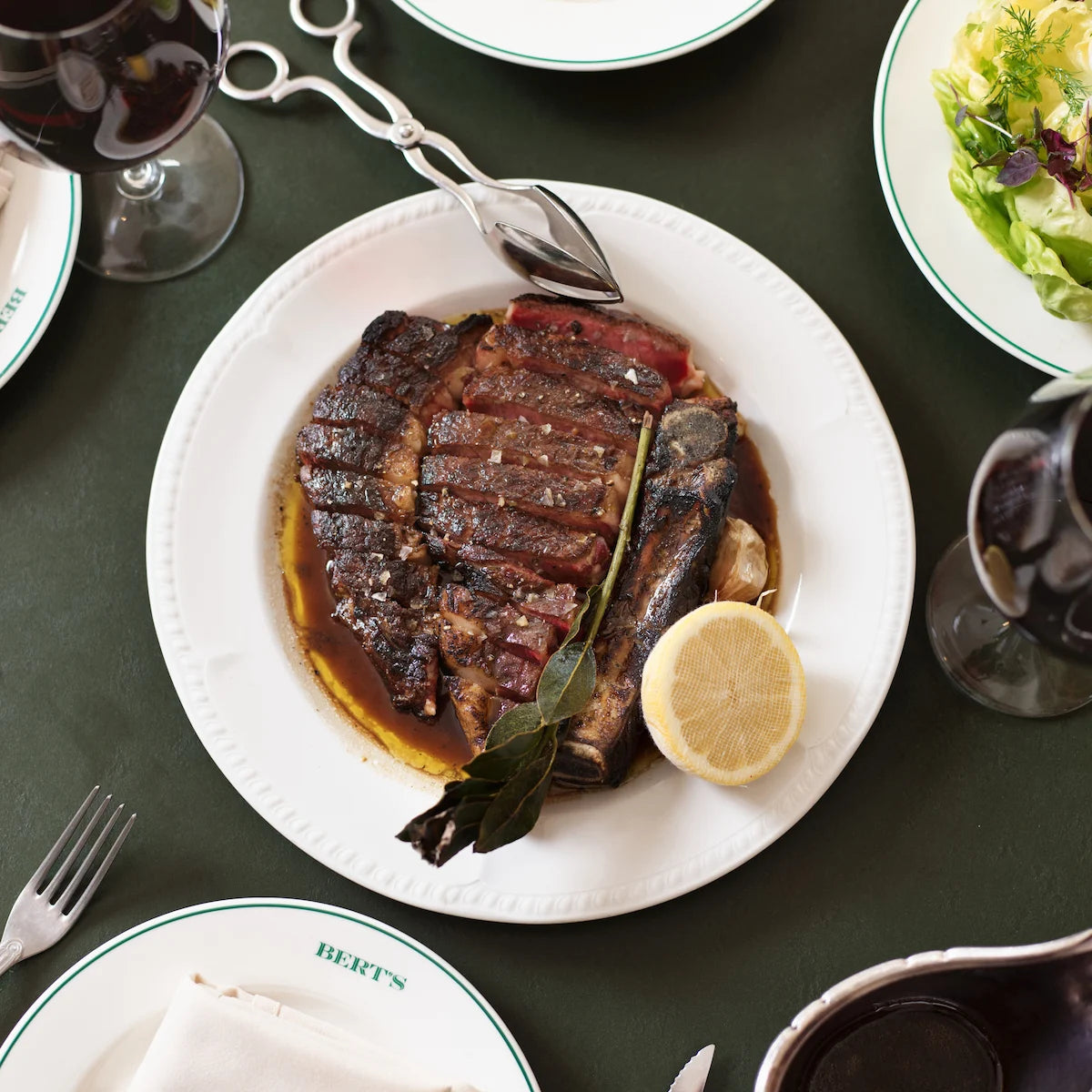 Steak dish on a white plate with lemon and herbs, served at Bert's Brasserie at Newport on Sydney's Northern Beaches.