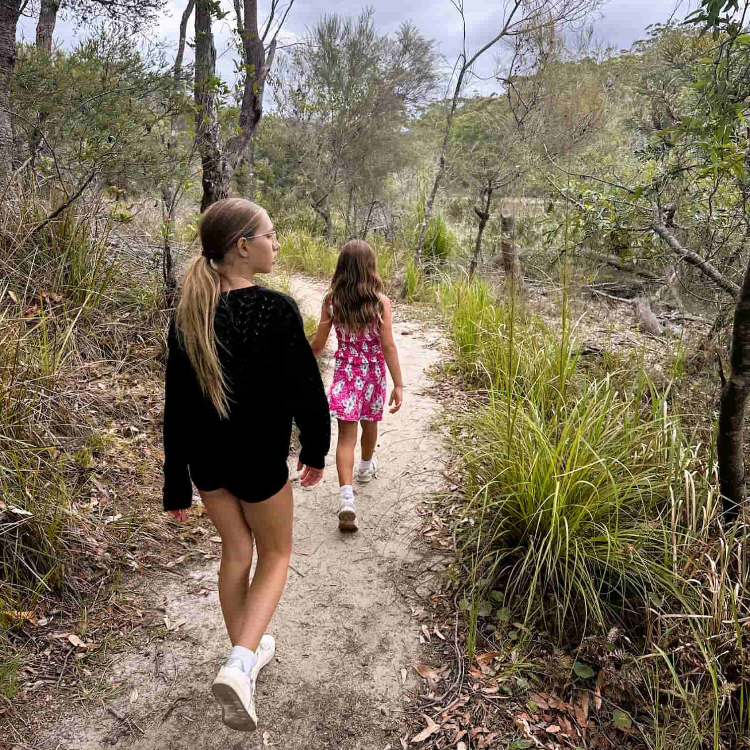 Two young girls walking on a bush trail at Manly Dam, in Manly Beach on Sydney's Northern Beaches.