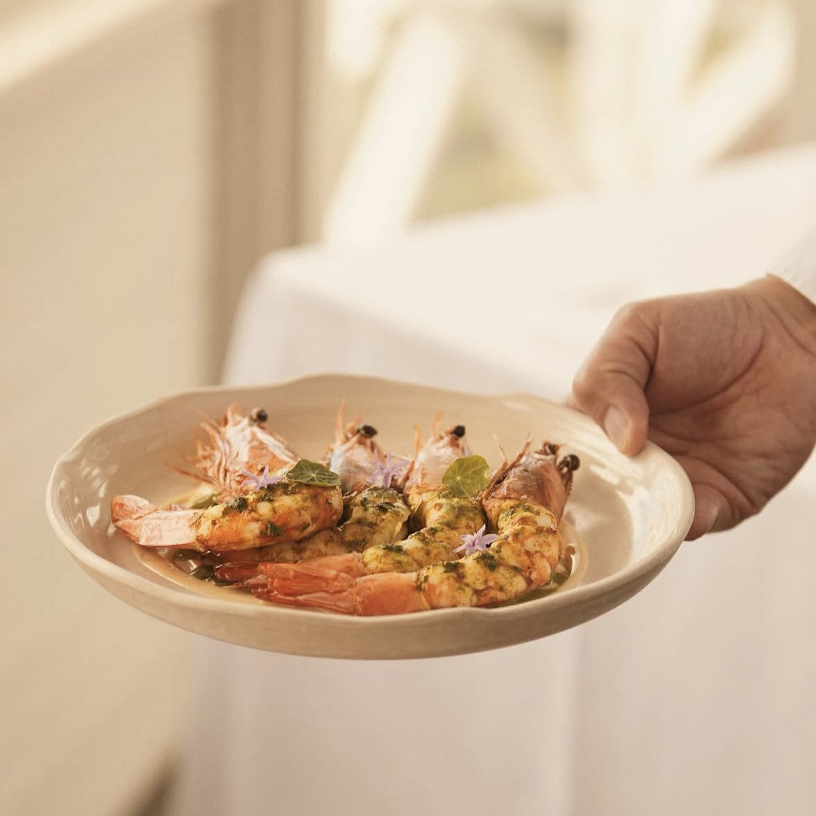 Hand holding a plate of shrimp at Pilu Restaurant in Freshwater on Sydney Northern Beaches