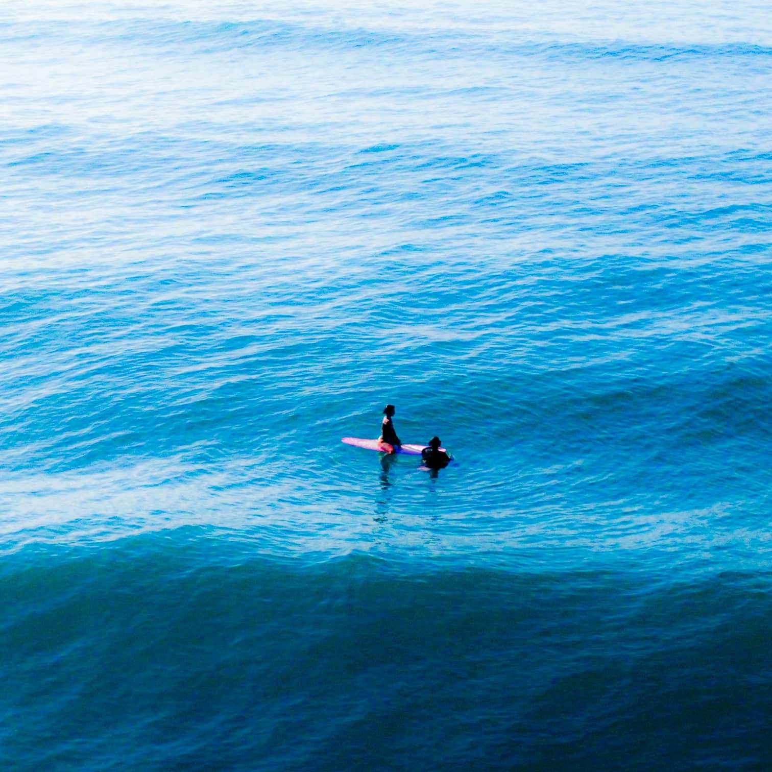 Two people on a surfboard in the ocean blue water in Manly Beach on Sydney's Northern Beaches.