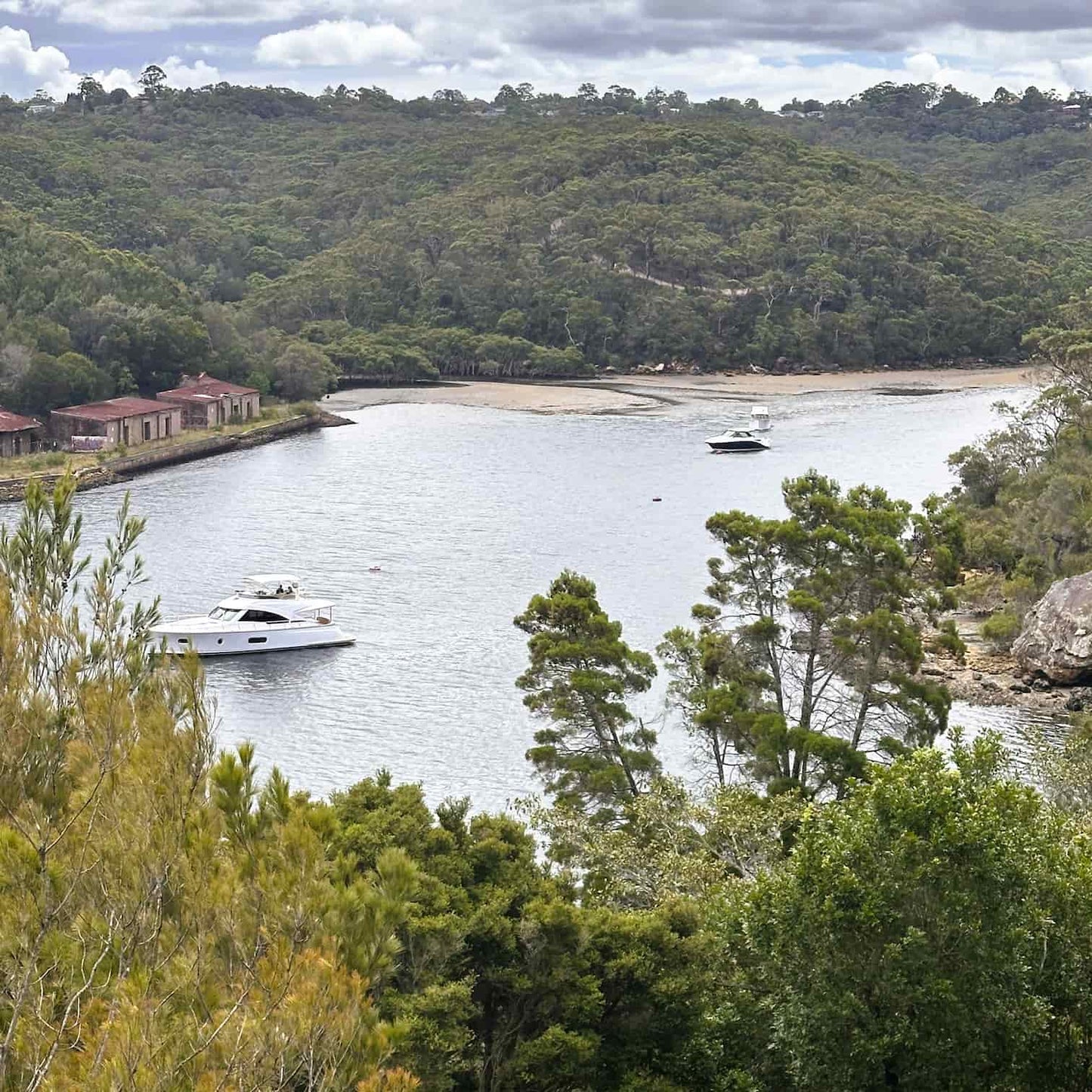 Lagoon surrounded by trees with a house and boat in the background in Bantry Bay in the Garigal National Park on Sydney's Northern Beaches.